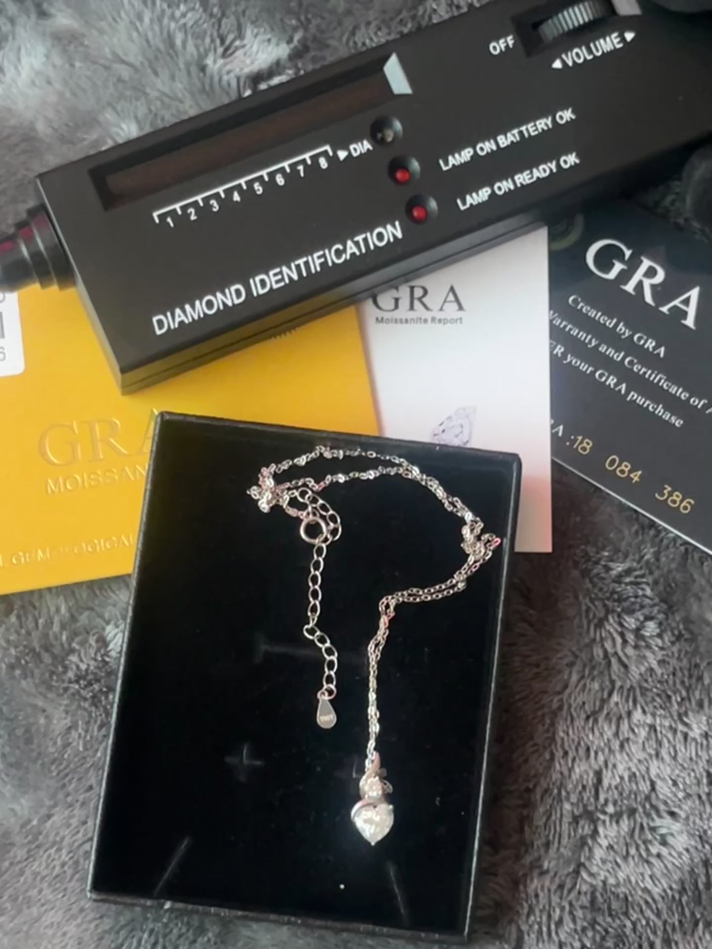 A silver-toned heart-shaped pendant necklace displayed inside a black jewelry box.